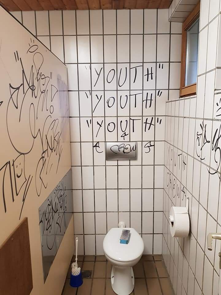 WC mit Graffiti an Wänden und Fliesen – vor der Reinigung